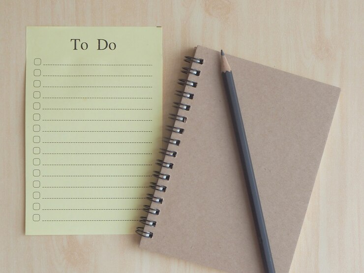 Soft-Focus To-Do-List-Papier mit Kontrollkästchen mit schwarzem Stift auf einem hellbraunen Notebook