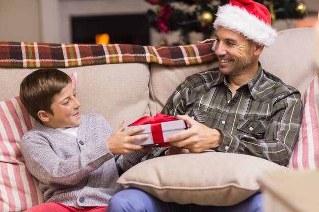 Sohn, der Vater ein Weihnachtsgeschenk auf der Couch gibt