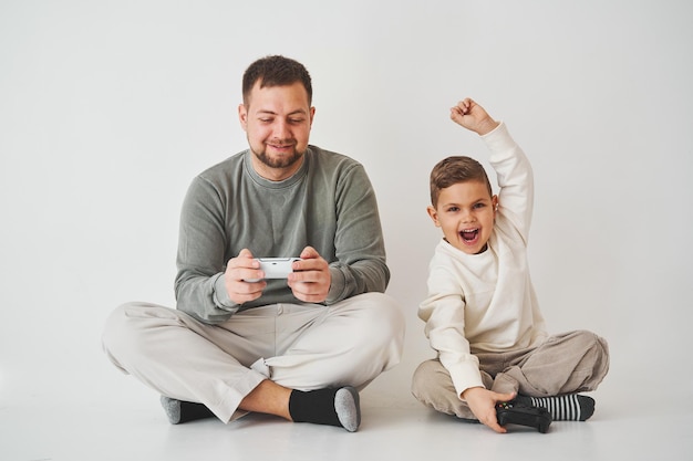 Sohn gewann Vater im Spiel auf der Konsole Glückliches Kind mit Gamepad hebt die Hände hoch und freut sich über den Sieg im Spiel