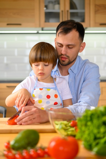 Sohn und Vater schneiden Tomaten