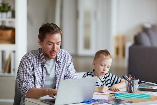 Sohn zeichnet, während Vater arbeitet