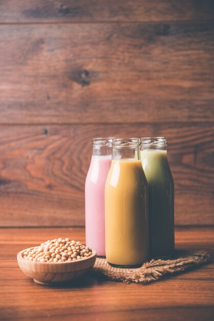 Soja O Leche de soja hecha remojando y moliendo semillas de soja, es una bebida saludable que se sirve en una botella con entera cruda en un tazón.