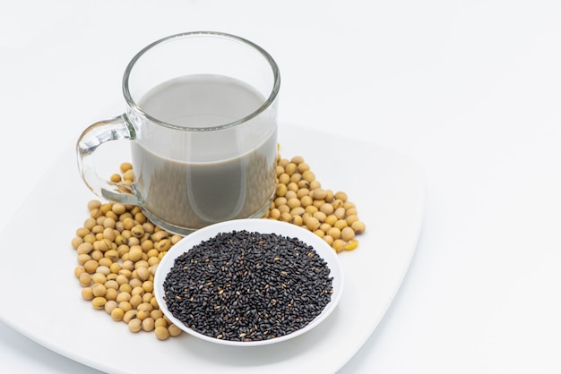 Sojamilch mit schwarzem indischem Sesam im Glas auf weißem Hintergrund.