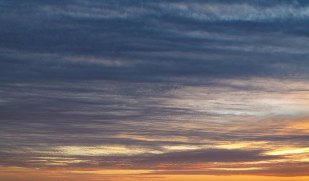 Sol al atardecer con cielo colorido y nubes.