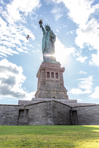 Foto sol atrás da estátua da liberdade como um pássaro voando para o quadro