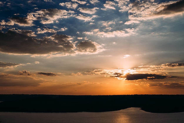 Sol brillando desde las nubes en la hermosa bahía durante el amanecer