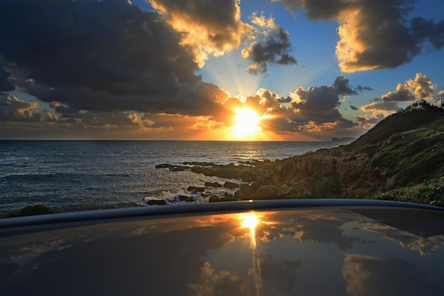 Sol brillante reflejado en la azotea de un coche junto al mar