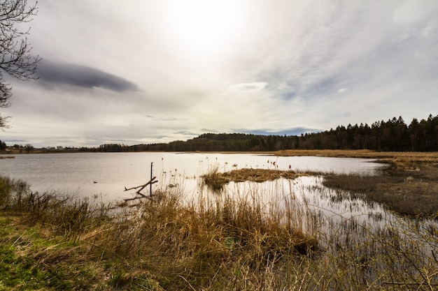 Sol detrás de las nubes sobre el lago, Gjennestadvannet, Stokke, Vestfold en Noruega