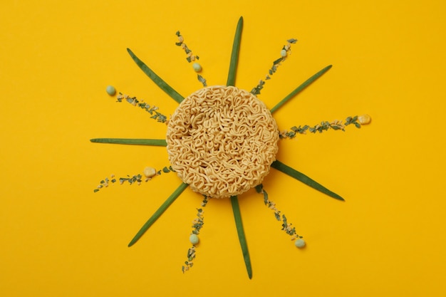 Sol feito de macarrão instantâneo e especiarias em fundo amarelo