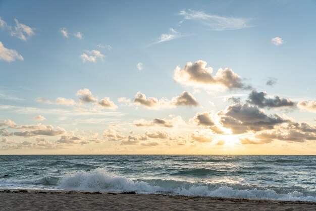 Sol nascente no horizonte acima de um oceano ou mar. no céu azul nuvens brancas