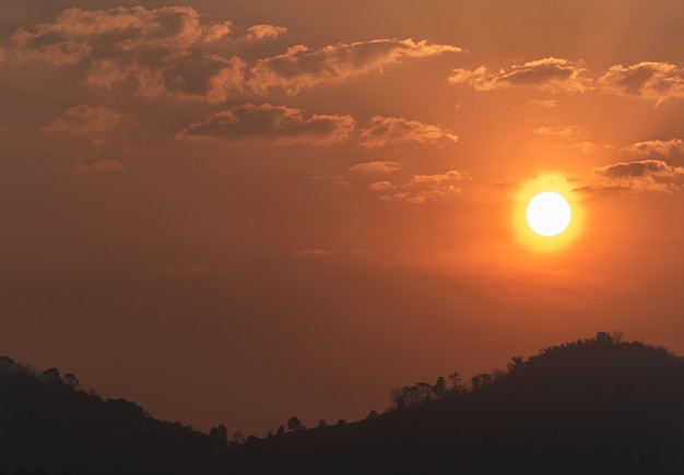 Sol no céu alaranjado da manhã e a vista da montanha