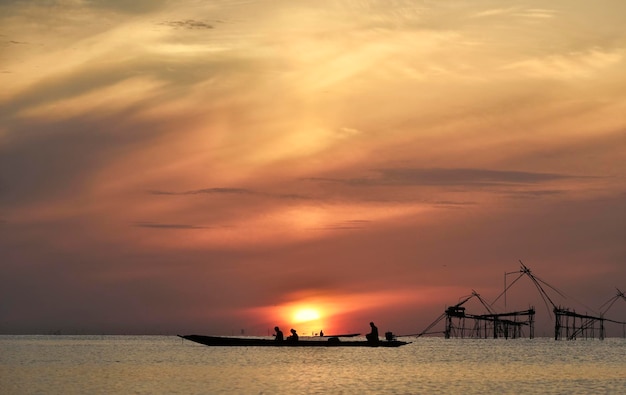 Sol omega detrás de la silueta del barco de pesca y una gran trampa de pesca