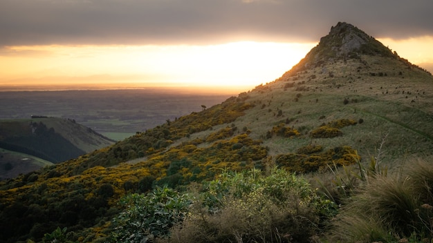 El sol se pone detrás de una montaña de forma inusual colinas de nueva zelanda