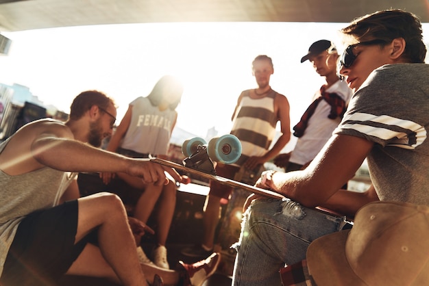 Foto sol quente e melhores amigos. grupo de amigos skatistas saindo juntos enquanto descansam sob a ponte ao ar livre