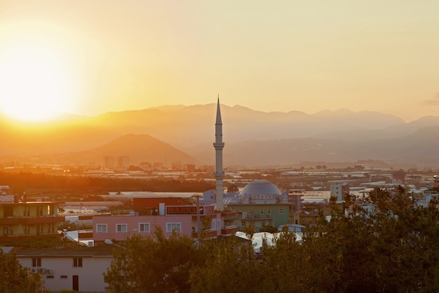 El sol sale de las montañas e ilumina la ciudad con una mezquita Turquía Alanya