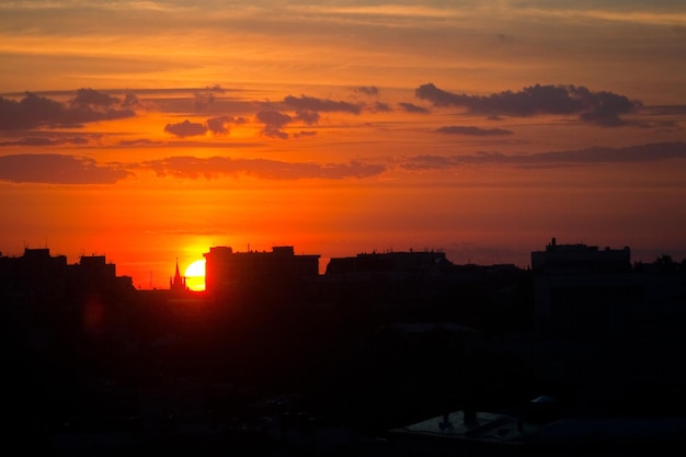 El sol de verano desdibuja la hora dorada del cielo del atardecer con una vista de la azotea de la ciudad contra el telón de fondo del edificio de oficinas de la ciudad Paisaje urbano cálido calor horizonte
