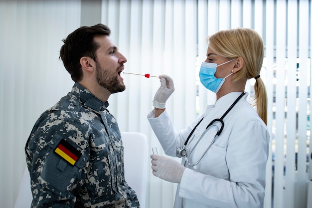 Soldado alemán en uniforme haciendo una prueba de PCR en el consultorio médico durante la epidemia del virus covid19