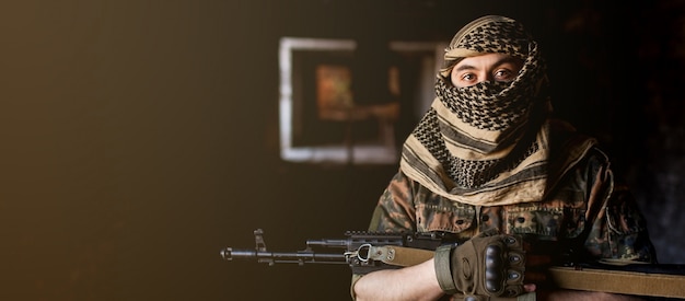 Soldado árabe masculino em um cocar do keffiyeh nacional com armas nas mãos