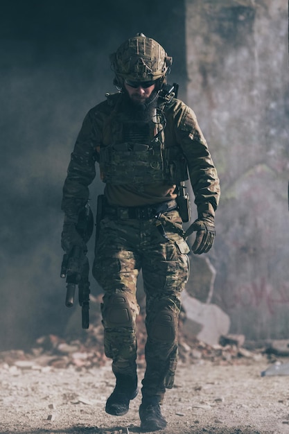 Un soldado barbudo en un uniforme de las fuerzas especiales camina a través de un edificio abandonado después de una misión exitosa.