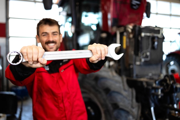 Foto un soldado caucásico feliz con una herramienta de llave preparada para reparar un tractor para la agroindustria