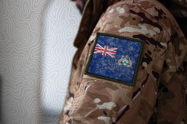 Soldado da Ilha de Ascensão Soldado com bandeira da Ilha de Ascensão Bandeira da Ilha de Ascensão em uniforme militar Vestuário de camuflagem