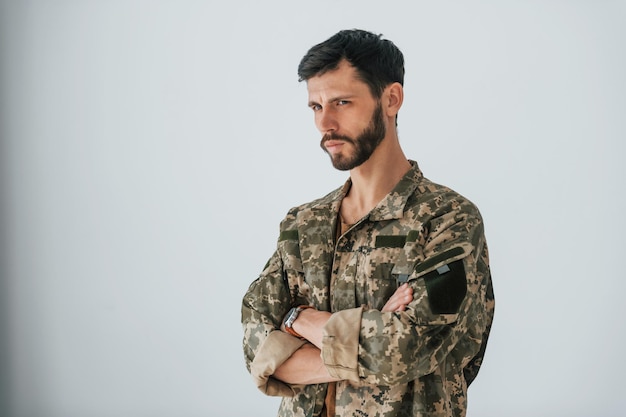 Soldado de uniforme está dentro de casa contra a parede branca