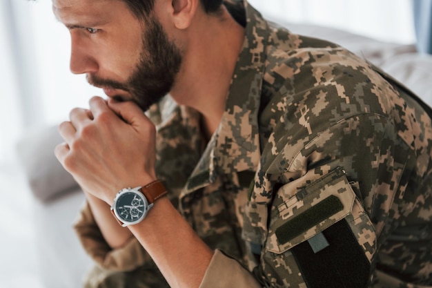 Soldado de uniforme está dentro de casa na sala doméstica