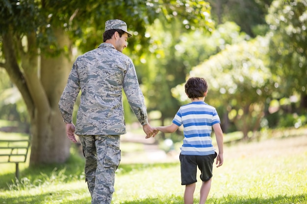 Soldado do exército andando com o menino no parque