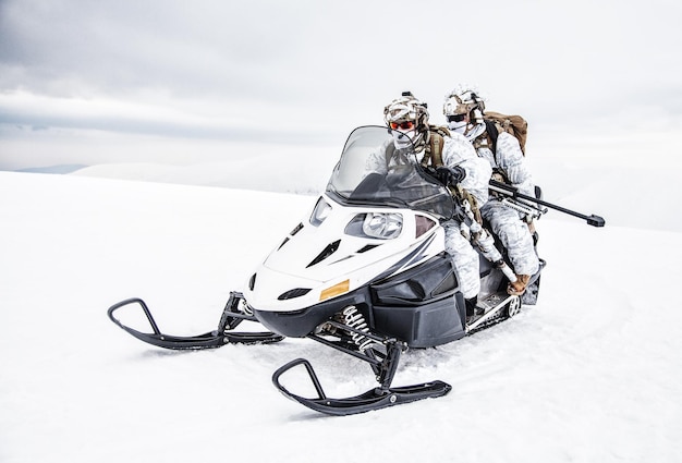 Soldado do exército em camuflagem de inverno em algum lugar do Ártico, movendo-se pelo campo de neve em uma moto de neve rastreada