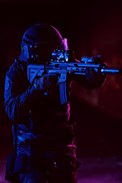 Soldado do exército em uniformes de combate com um rifle de assalto e fundo escuro de missão noturna de capacete de combate. Efeito de luz em gel azul e roxo. Foto de alta qualidade