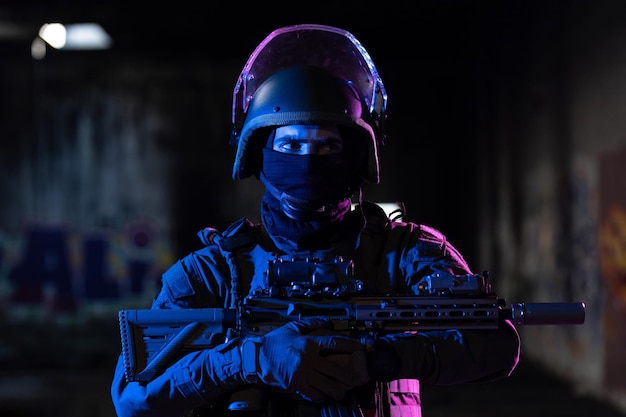 Soldado do exército em uniformes de combate com um rifle de assalto e fundo escuro de missão noturna de capacete de combate. Efeito de luz em gel azul e roxo. Foto de alta qualidade