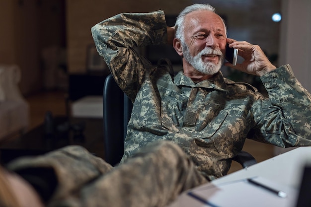 Foto soldado do exército falando por telefone inteligente enquanto estava sentado em uma cadeira