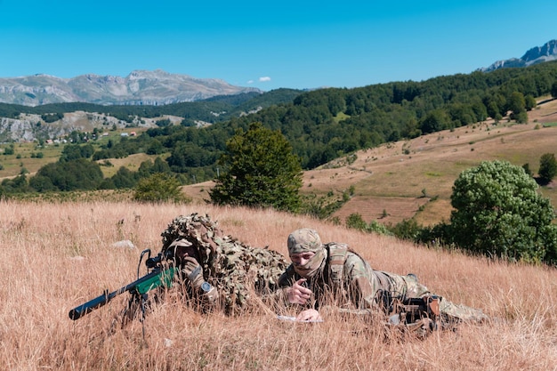 Soldado do exército segurando rifle sniper com mira e mirando na floresta. Conceito de guerra, exército, tecnologia e pessoas.