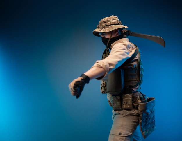 Un soldado del ejército con ropa militar se balancea para golpear con un machete en la mano