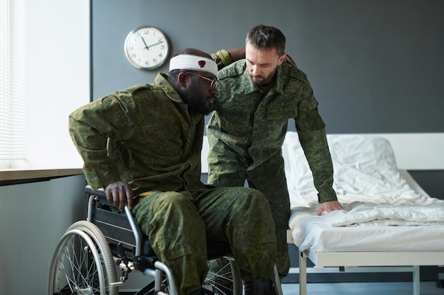 Soldado em uniforme militar ajudando seu amigo ferido em cadeira de rodas