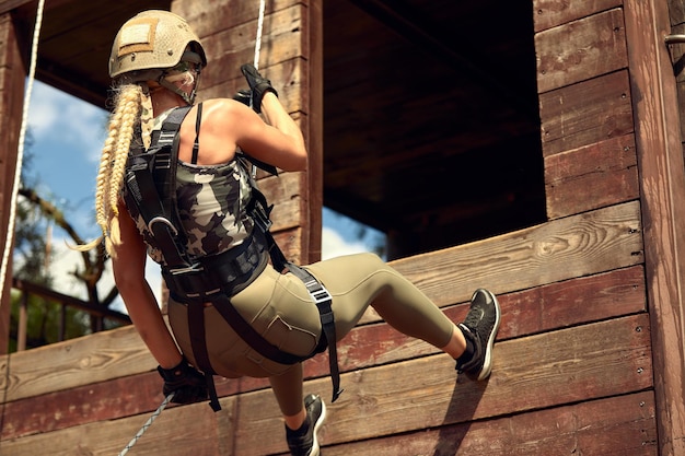 Foto soldado entrenando en rappel con cuerda mujer militar colgando de equipo de escalada