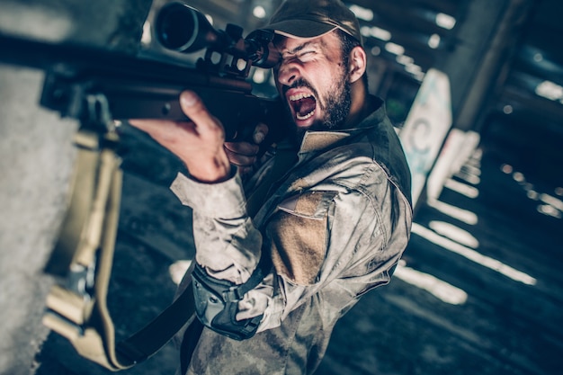 Soldado está desnatado. Ele está olhando pelas lentes porque está mirando. Guy é redady para atirar com o rifle.