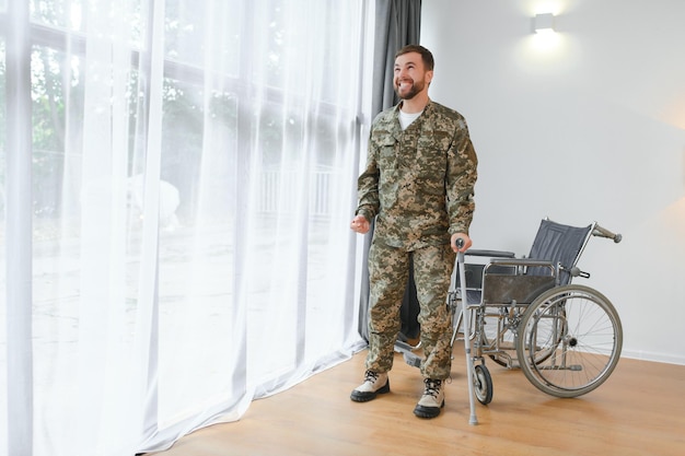 Soldado feliz en uniforme militar levantándose de la silla de ruedas Concepto de rehabilitación de veteranos