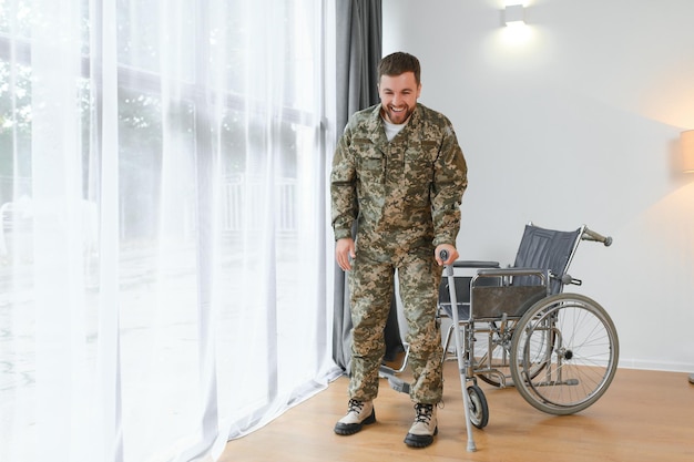 Soldado feliz en uniforme militar levantándose de la silla de ruedas Concepto de rehabilitación de veteranos