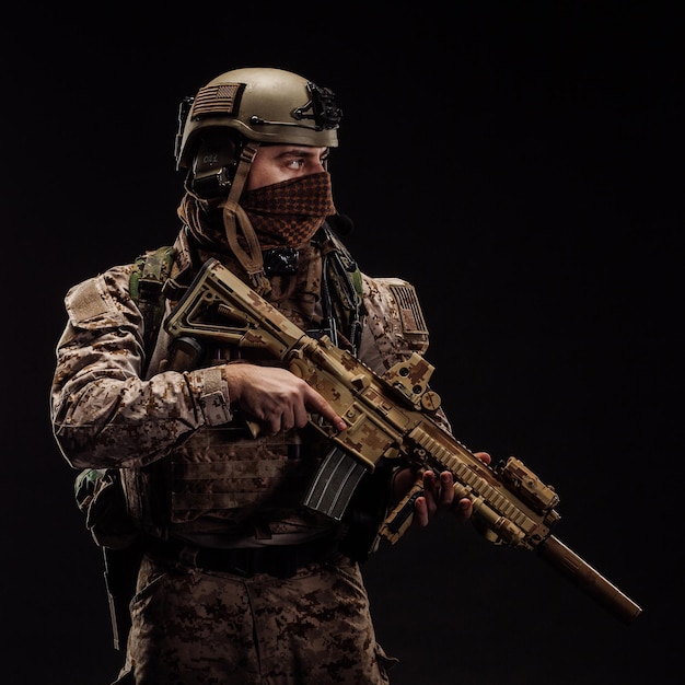 Soldado de las fuerzas especiales de los Estados Unidos o contratista militar privado sosteniendo un rifle Imagen sobre un fondo negro