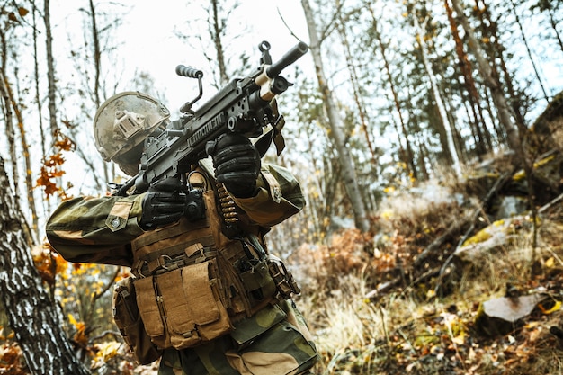 Soldado de las fuerzas especiales de reacción rápida noruego FSK disparando en el bosque. Los uniformes de camuflaje de campo, el casco de combate y las gafas protectoras están puestos