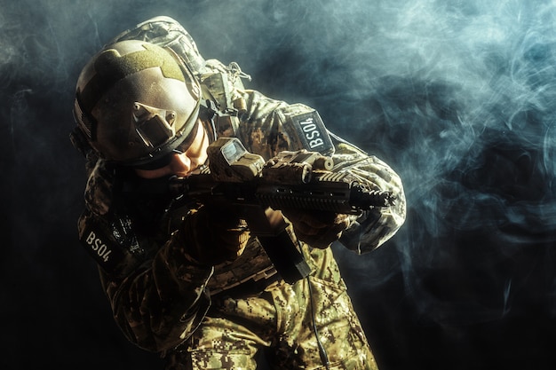 Soldado de las fuerzas especiales con rifle sobre fondo oscuro