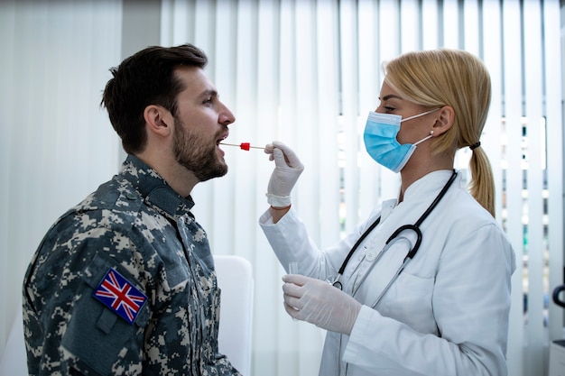 Soldado inglés en uniforme haciendo una prueba de PCR en el consultorio médico durante la epidemia del virus covid19