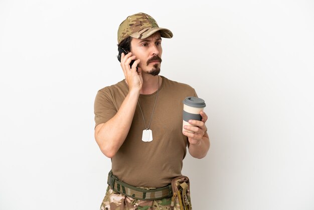 Soldado isolado no fundo branco segurando um café para levar e um celular