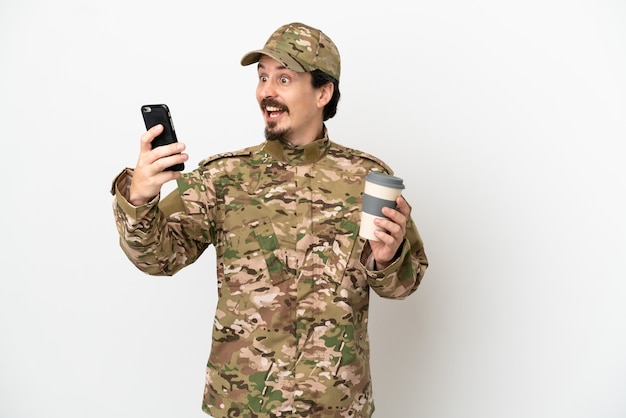 Soldado isolado no fundo branco segurando um café para levar e um celular