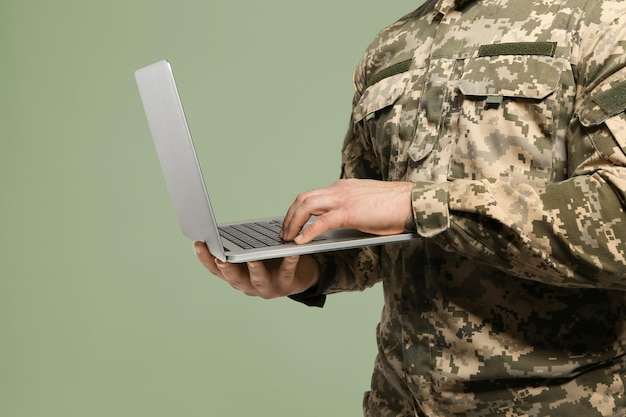 Soldado con laptop en primer plano de fondo gris