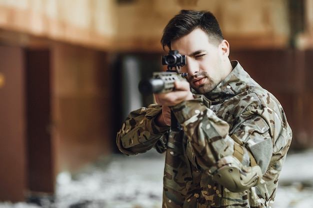 Un soldado militar apunta y sostiene un rifle grande en el edificio.