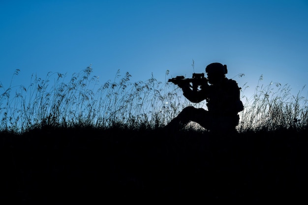 Soldado militar com armas ao pôr do sol atirou segurando o conceito militar de céu colorido de arma