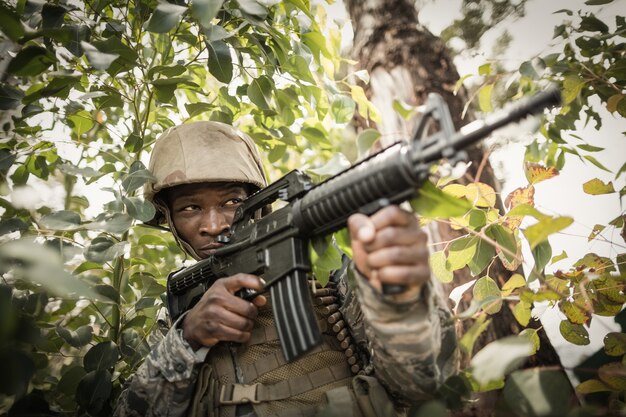 Atirador furtivo camuflado na floresta em emboscada. militar apontando uma  arma, um rifle para o inimigo na natureza. exército, airsoft, hobby,  conceito de jogo