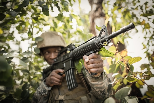 Atirador furtivo camuflado na floresta em emboscada. militar apontando uma  arma, um rifle para o inimigo na natureza. exército, airsoft, hobby,  conceito de jogo